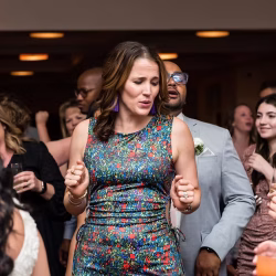 Corporate Events A woman in a colorful dress dances among a group of people at an indoor social event.